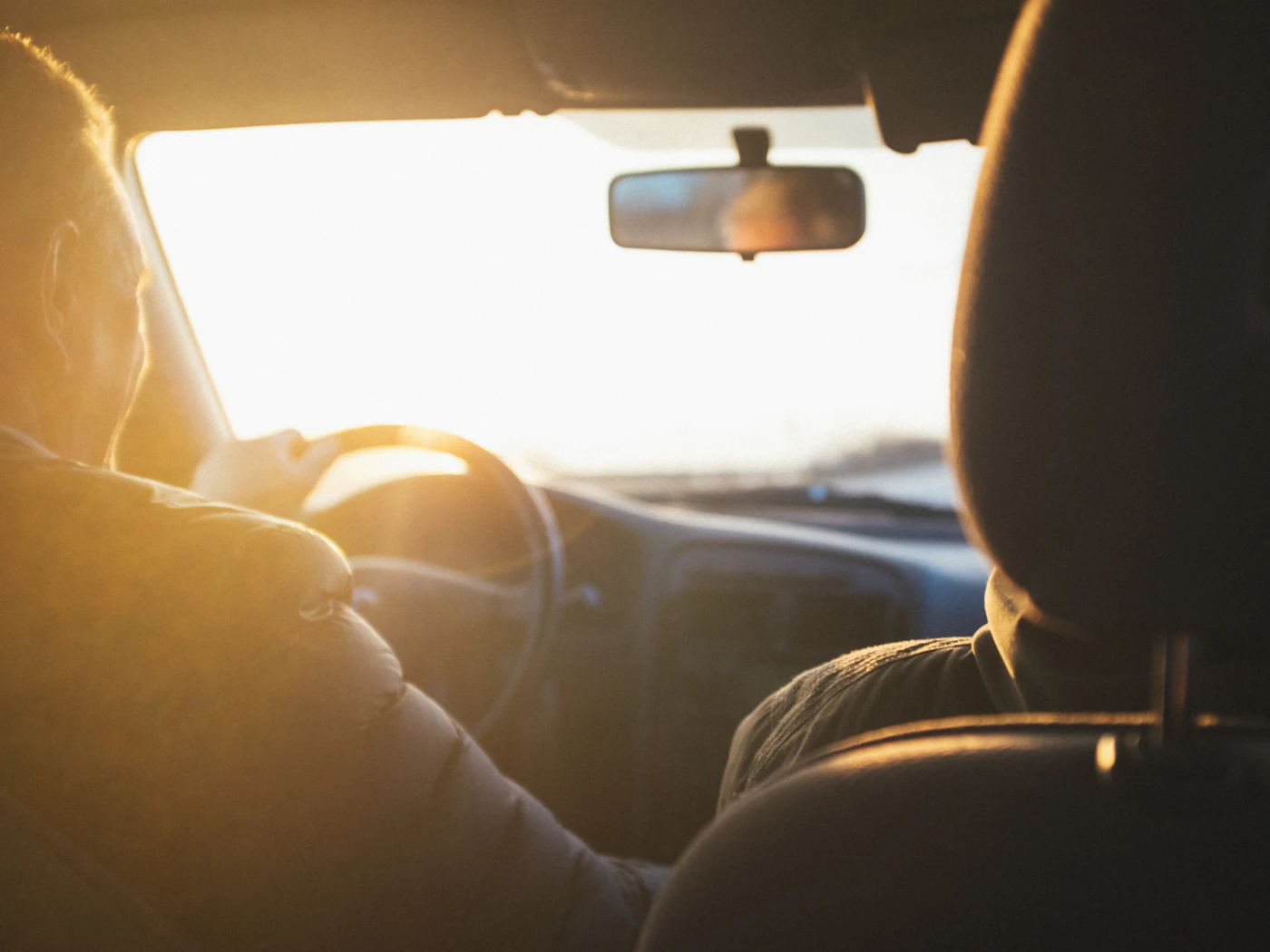 A driver at the wheel on an open road at sunset